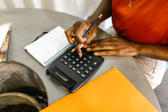 An African American woman using a calculator and notepad for budgeting. 4 things to understand about tax preparation pricing