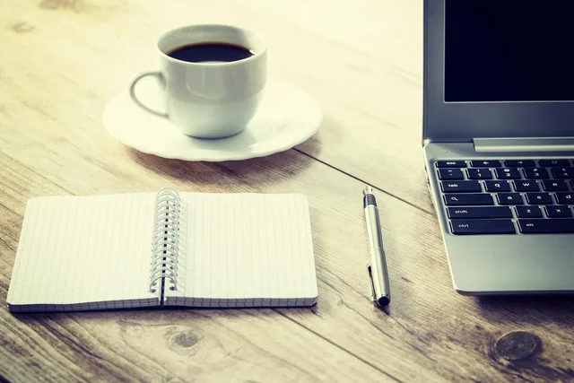 coffee, computer, cup, coffee cup, desk, drink, laptop, notebook, pen, table, wooden table, workspace, work from home. The tax preparation trend report for owners in 2027